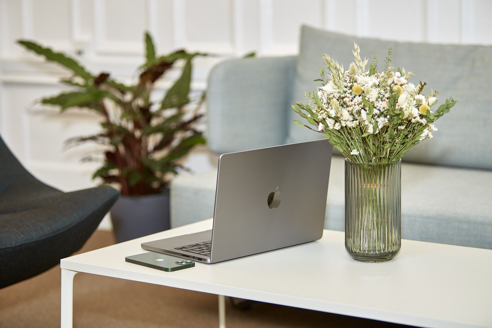 MacBook Pro, iPhone og blomster på et loungebord